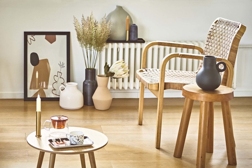 Déco scandicraft avec des pots artisanaux en terre cuite, un fauteuil en cannage et un tabouret en bois