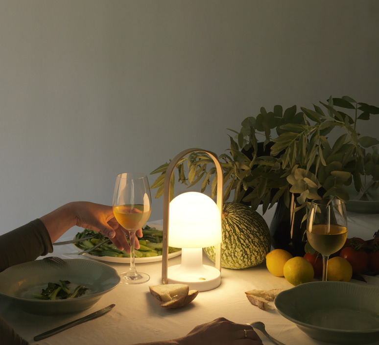 Un luminaire extérieur, de style design, éclaire cette table d'été dressée en soirée, à la déco naturelle