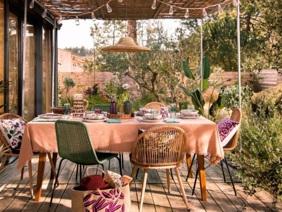 Une table d'été sur la terrasse, joliment décorée avec des couleurs pastel et des matériaux naturels