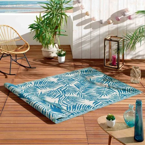 Décorer son balcon avec un tapis coloré, aux motifs végétaux, sur des lames de terrasse en bois