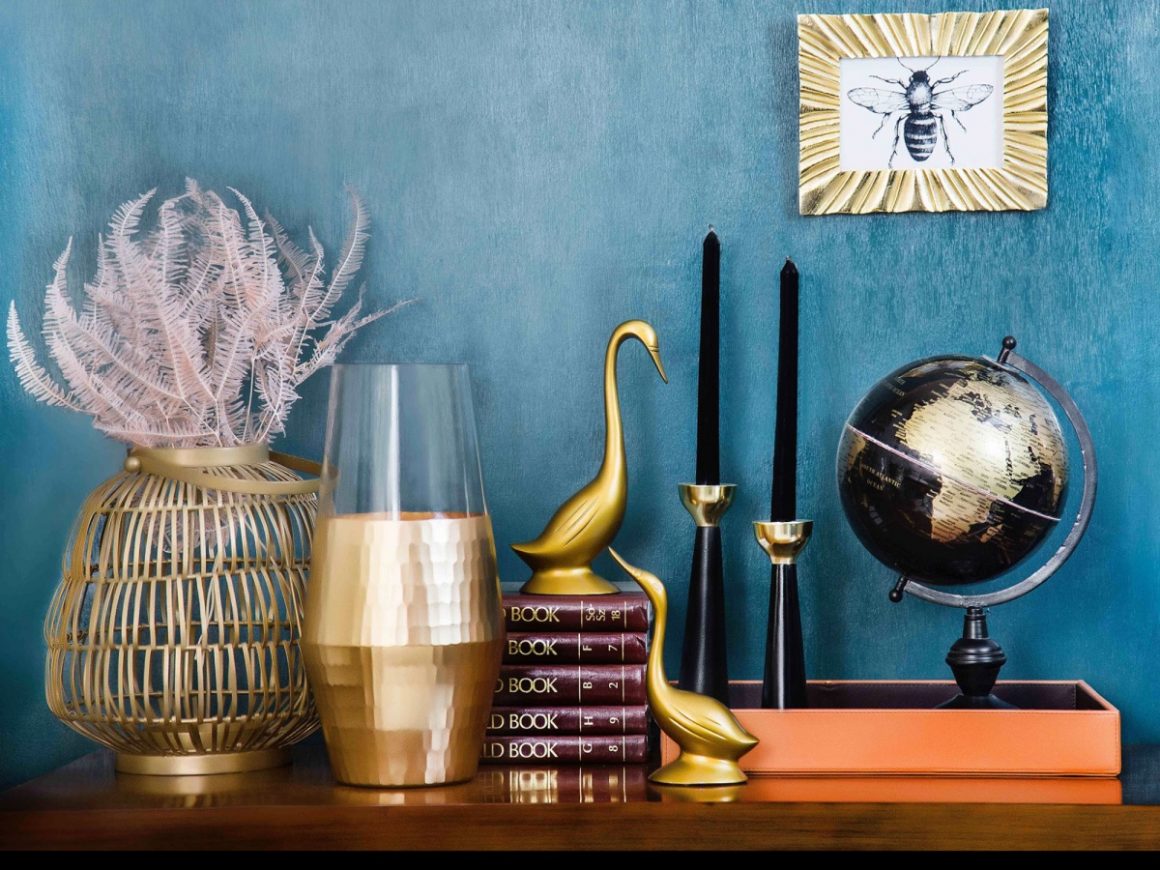 Un assortiment d'objets déco tendance sur la commode : des bougies, une mappemonde, des livres, une statuette, etc.
