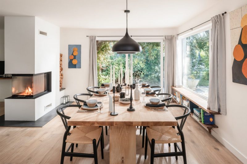La salle à manger scandinave est aménagée avec des chaises nordiques et une grande table en bois