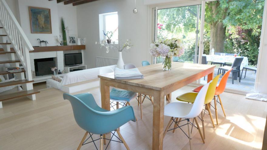 Une salle à manger scandinave, avec des chaises nordiques dans les tons pastel et printaniers