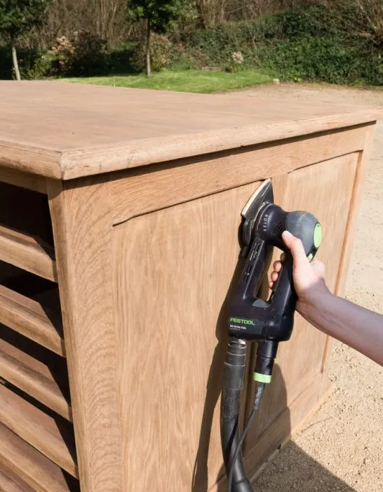 Rénover un meuble en bois à l'aide d'une ponceuse électrique, pour enlever les couches de vernis