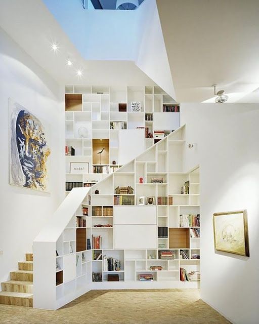 Un escalier moderne blanc, agrémenté d'une bibliothèque sur mesure