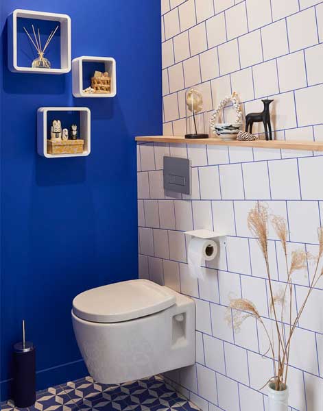 Il y a du carrelage sur le mur derrière les toilettes, et de la peinture bleue sur le côté