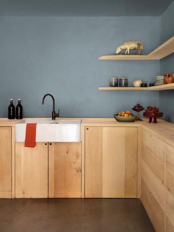 Le mur est bleu clair, et les meubles en bois clair, dans cette cuisine tendance et moderne