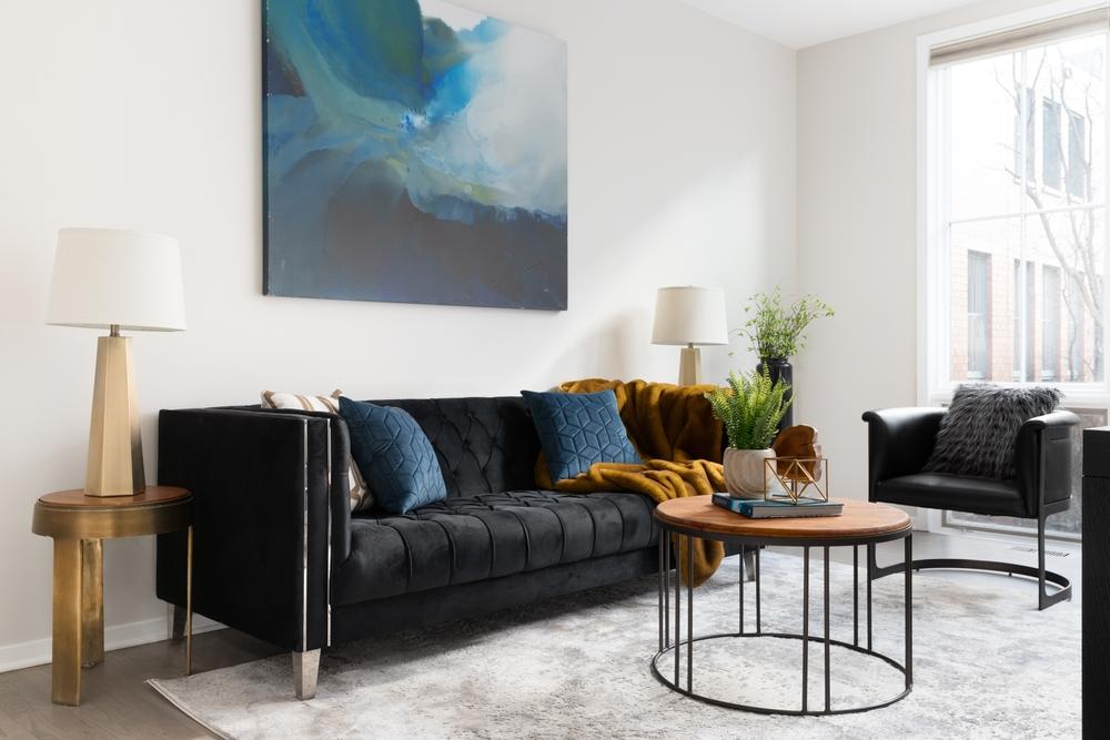 Une déco salon moderne chic avec un grand canapé noir, une table basse et un fauteuil designs, style scandinave