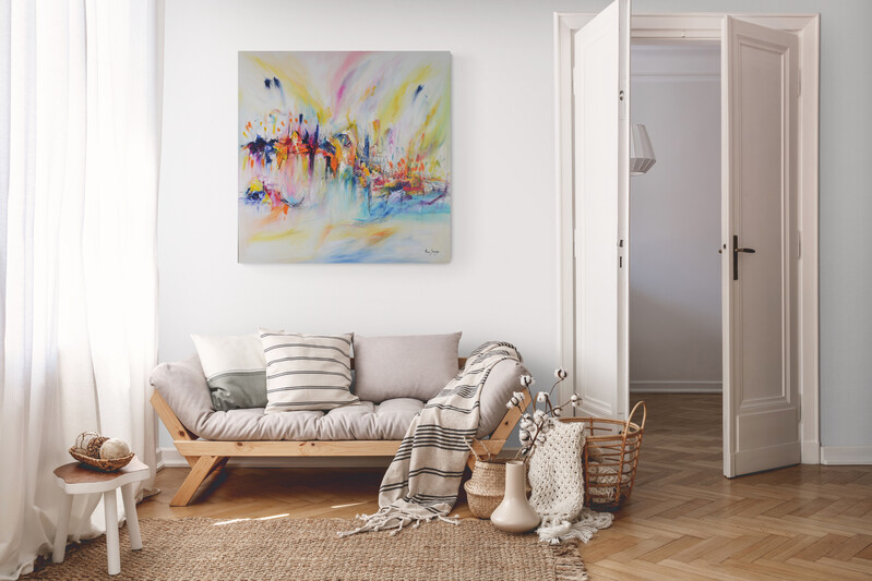 Un tableau abstrait très coloré au-dessus du canapé de style scandinave