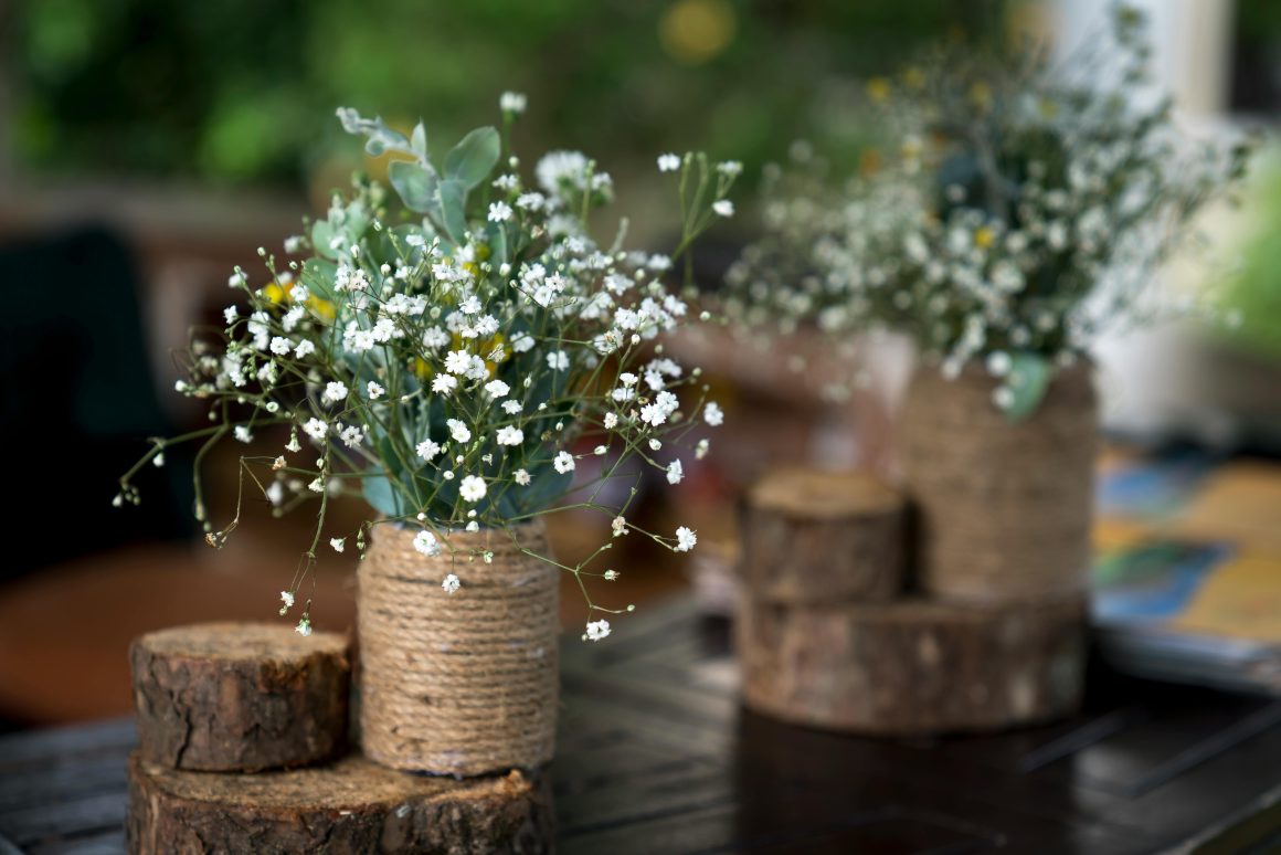 deux bouquets de fleurs blanches dans pots faits de corde posés sur des petits rondins de bois