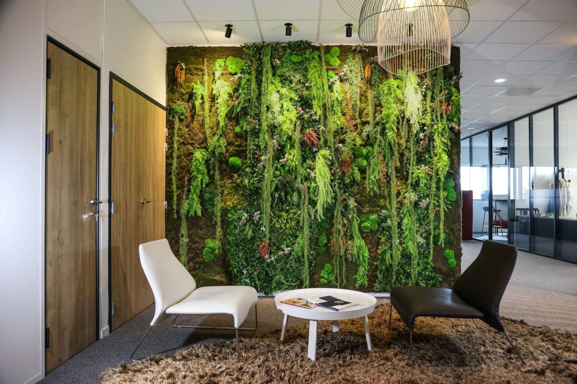Un grand mur végétal intérieur dans la salle d'attente ou de pause d'un bureau, avec deux élégants fauteuils et une table basse