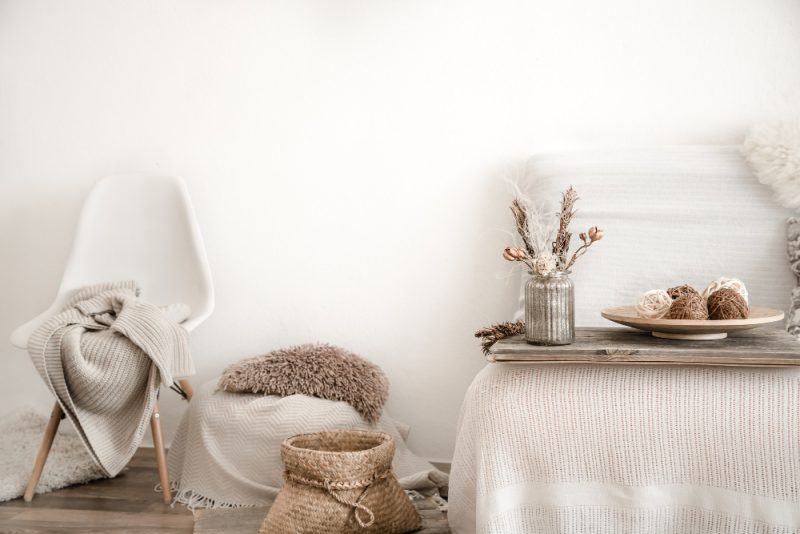 Déco intérieure dans les couleurs scandinaves, avec une chaise aux pieds fins, un pouf, un lit et une corbeille en osier