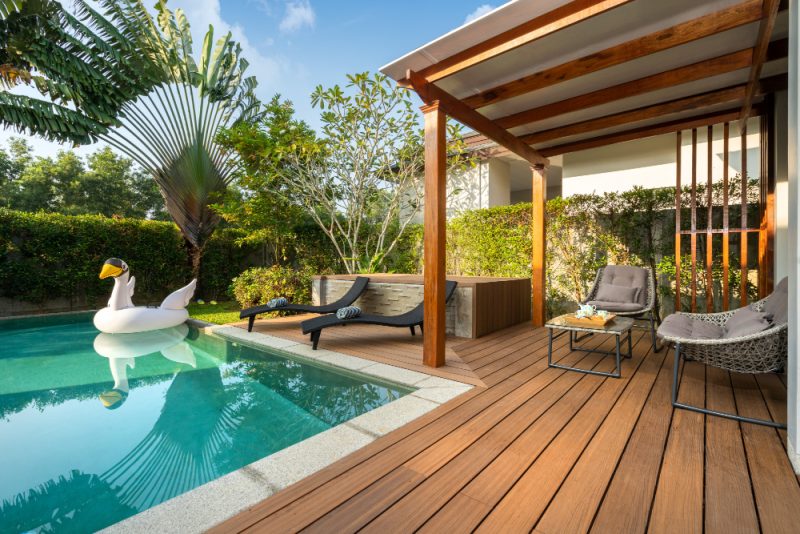 Une déco terrasse piscine en bois avec un pool house et des meubles tendance