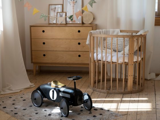 Du mobilier chambre bébé en bois, avec un petit berceau rond, une commode et une voiture vintage