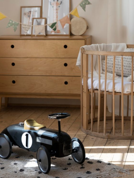 Du mobilier chambre bébé en bois, avec un petit berceau rond, une commode et une voiture vintage