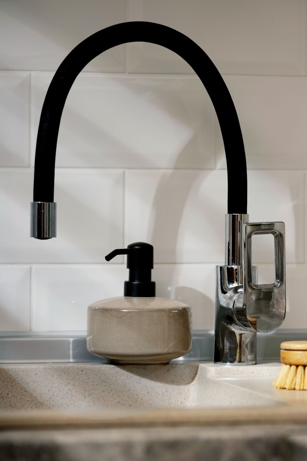 un robinet noir simple dans une cuisine avec un carrelage mural blanc 