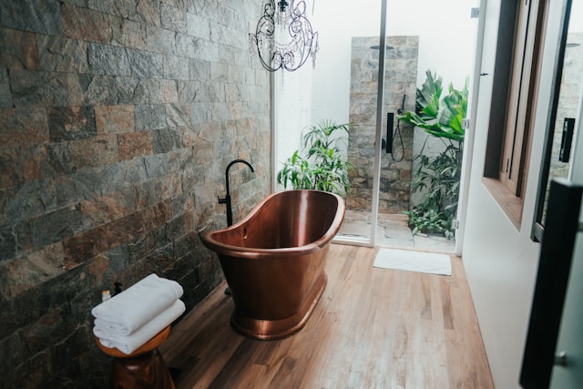 une idée déco pour une salle de bain tendance avec une baignoire en cuivre et un mur en pierre