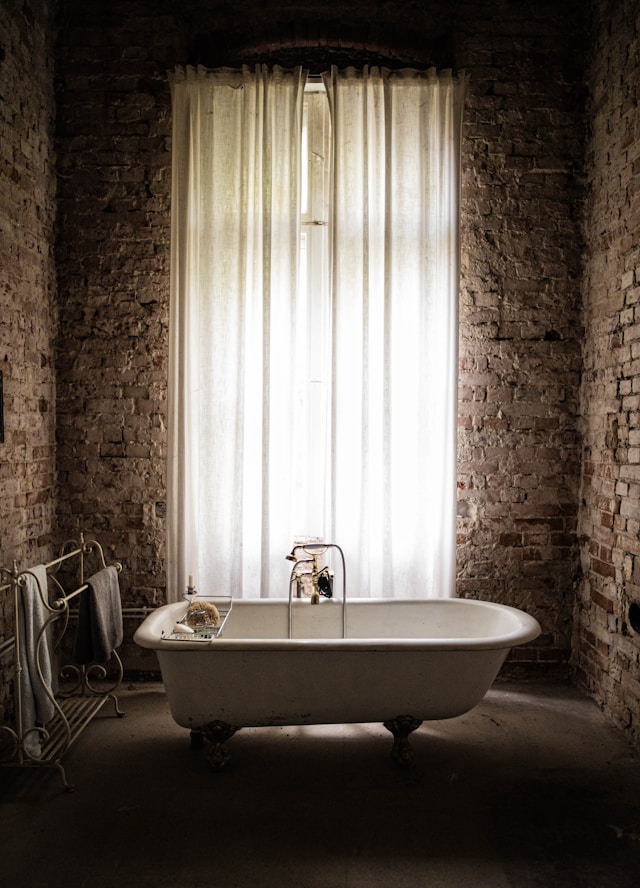 une salle de bain sombre décorée de murs en pierre avec baignoire au centre