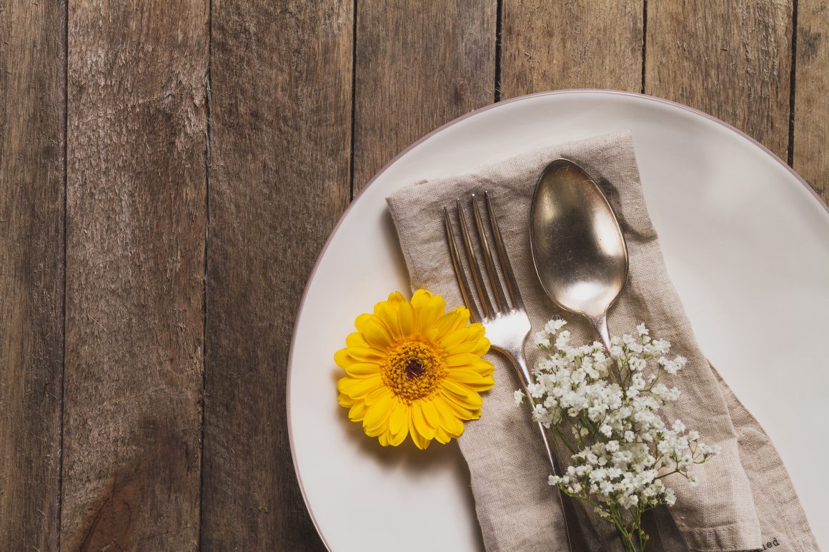 une serviette de table dans une assiette avec des fleurs et des couverts