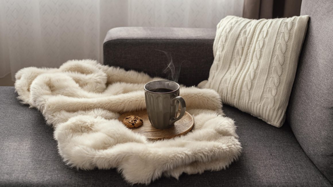 une couverture douce de couleur beige sur un canapé