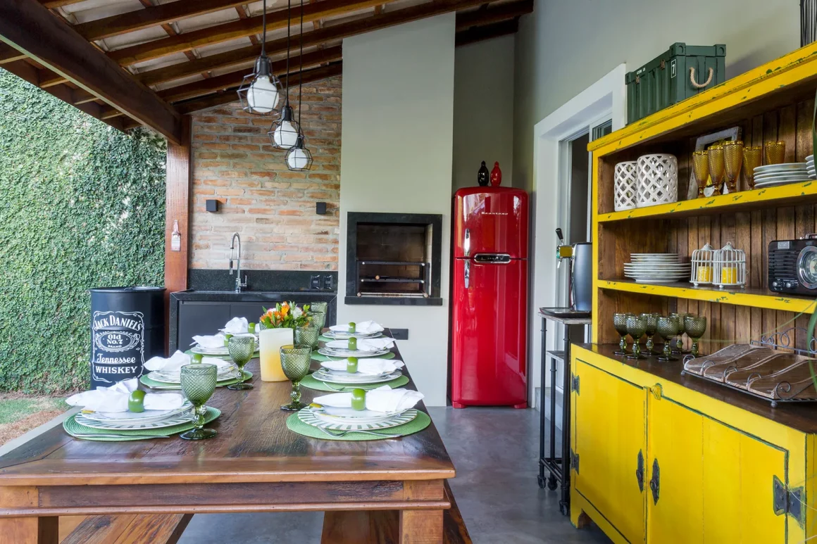 La cuisine extérieure sur la terrasse est très colorée, et il y a une grande table en bois pour déguster des barbecues entre amis