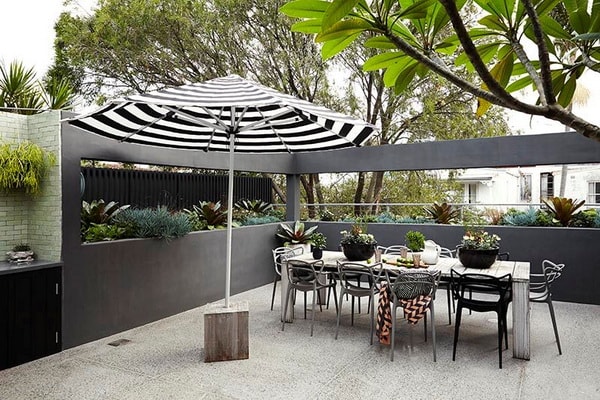 Une grande terrasse gris anthracite avec un parasol noir et blanc