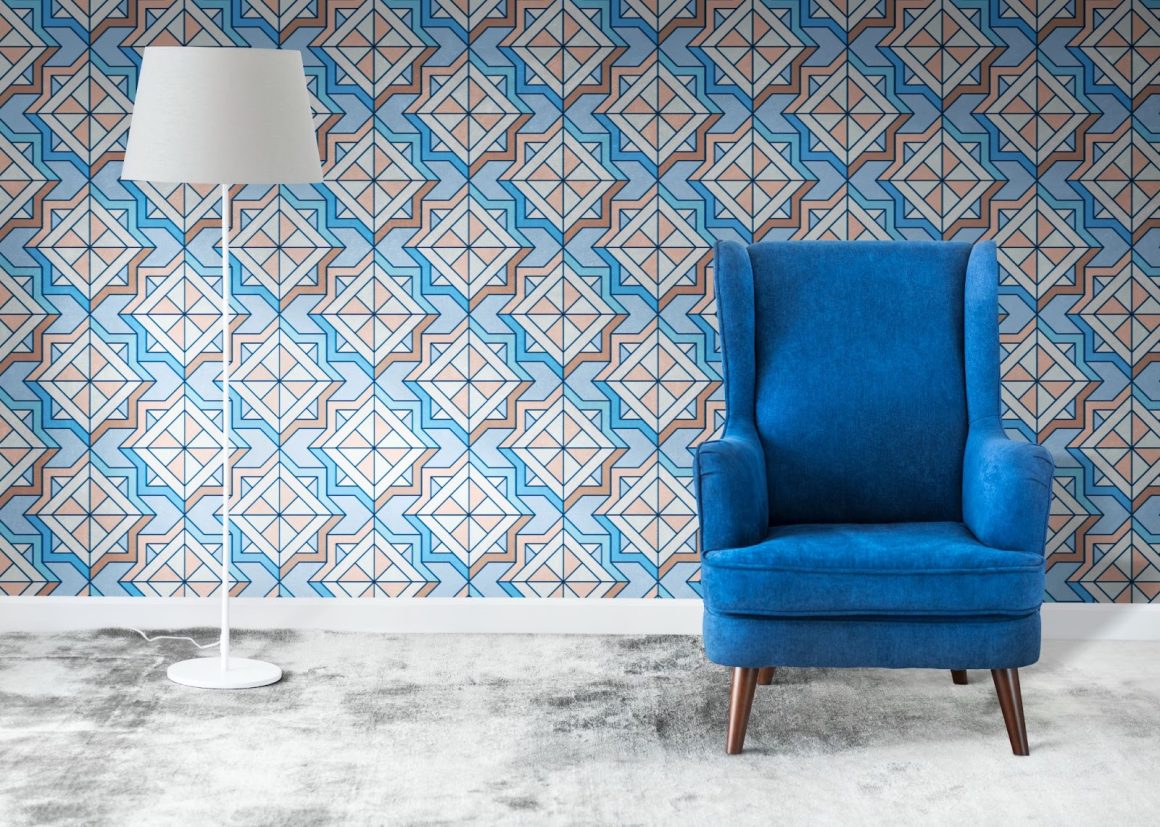 n fauteuil en velours bleu se trouve devant un mur à motif géométrique.