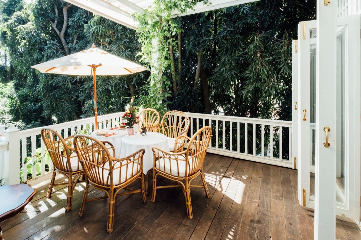 Une terrasse ombragée avec des chaises en osier et une table ronde, idéale pour un repas en plein air