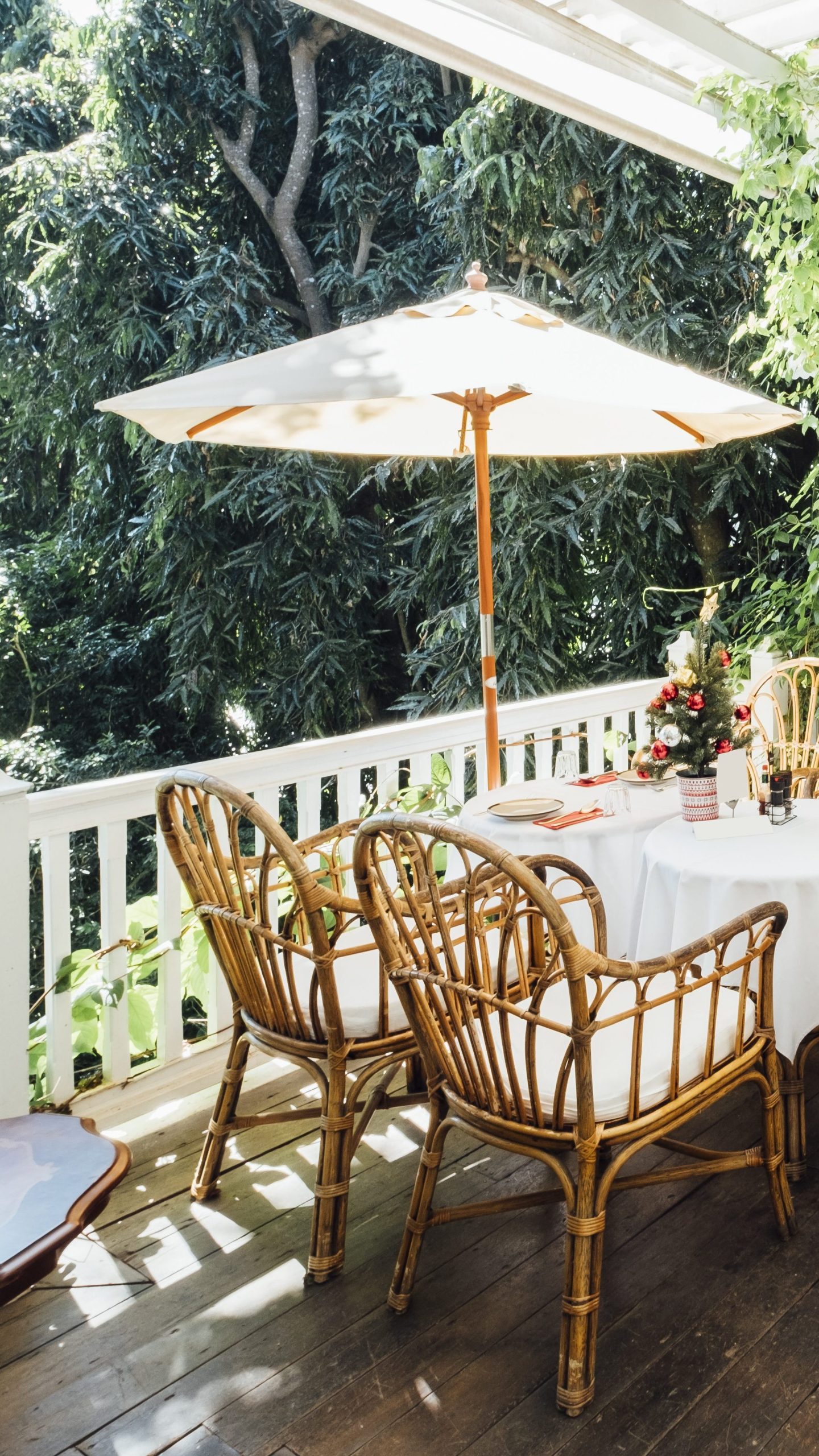 une terrasse ombragée avec des chaises en osier et une table ronde, idéale pour un repas en plein air