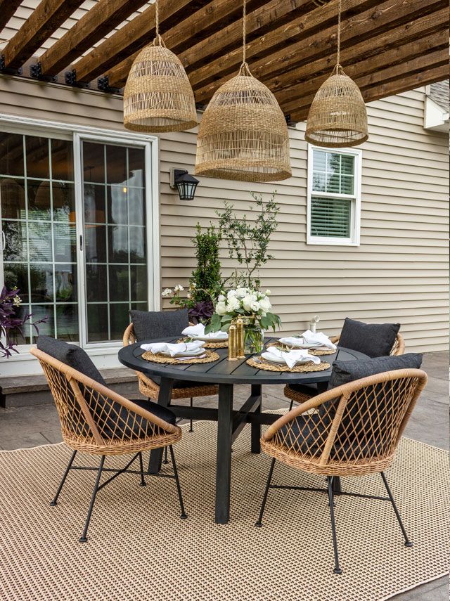 un coin repas extérieur sous une pergola en bois, décoré de luminaires suspendus et de chaises confortables