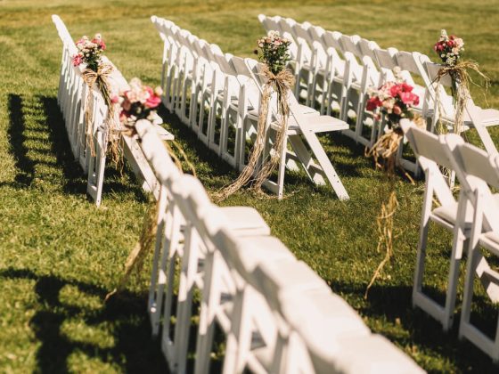 Une décoration mariage extérieur avec des chaises blanches des deux côtés de l'allée nuptiale