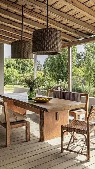 charmant coin repas extérieur sous une pergola en bois, avec une table rectangulaire et des chaises assorties, éclairées par des suspensions tressées, sur un sol en bois