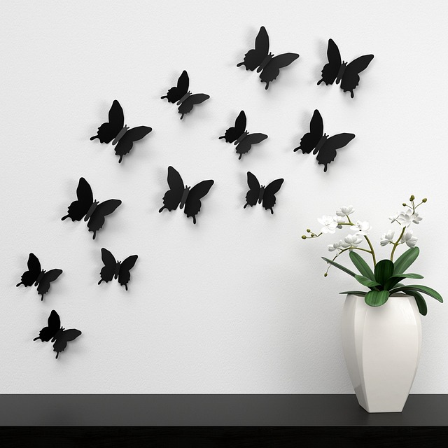 Plusieurs papillons noirs de tailles variées décorent un mur blanc.