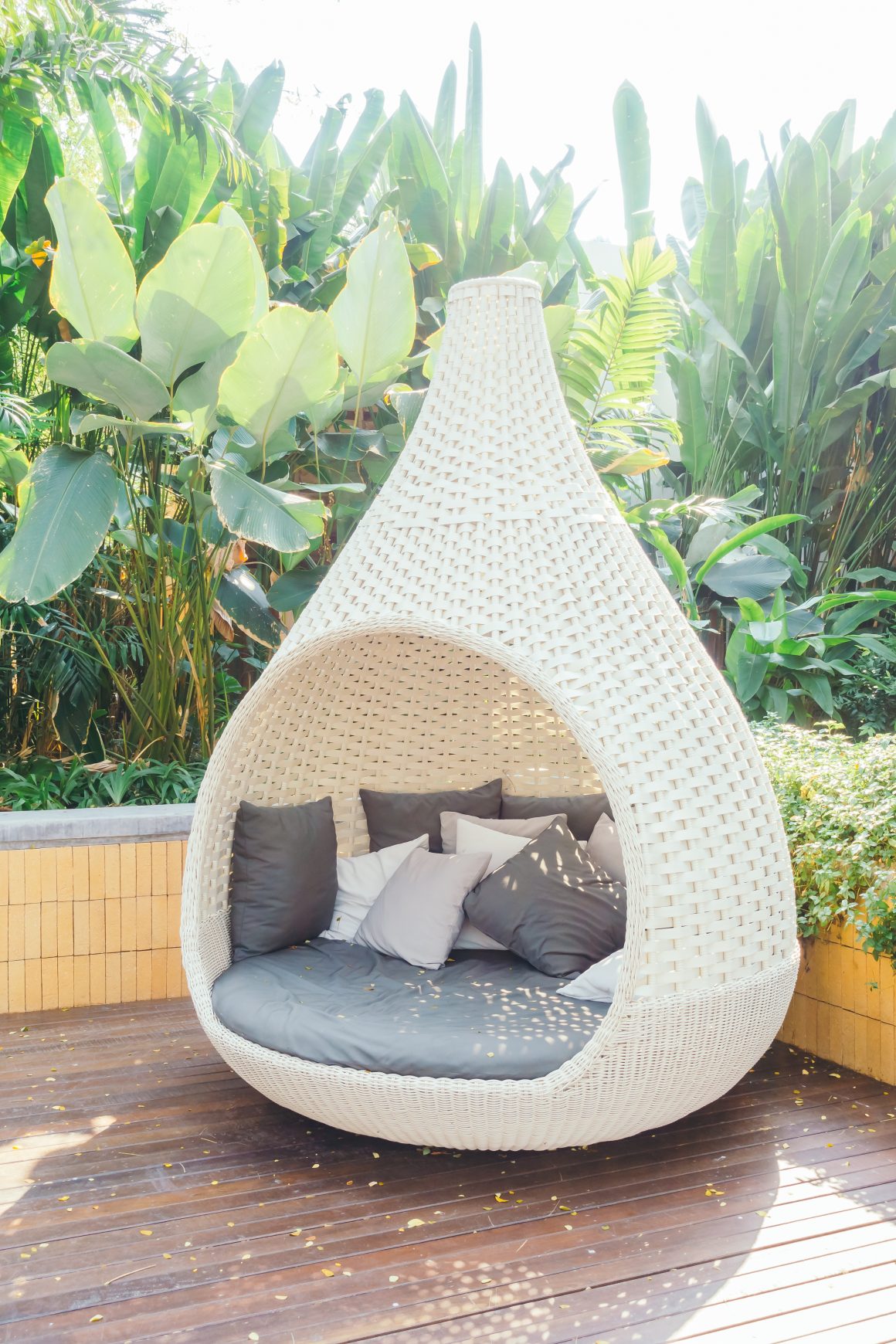 une chaise en forme d'œuf a l'extérieur faisant partie dune décoration tropicale entourée de verdure luxuriante