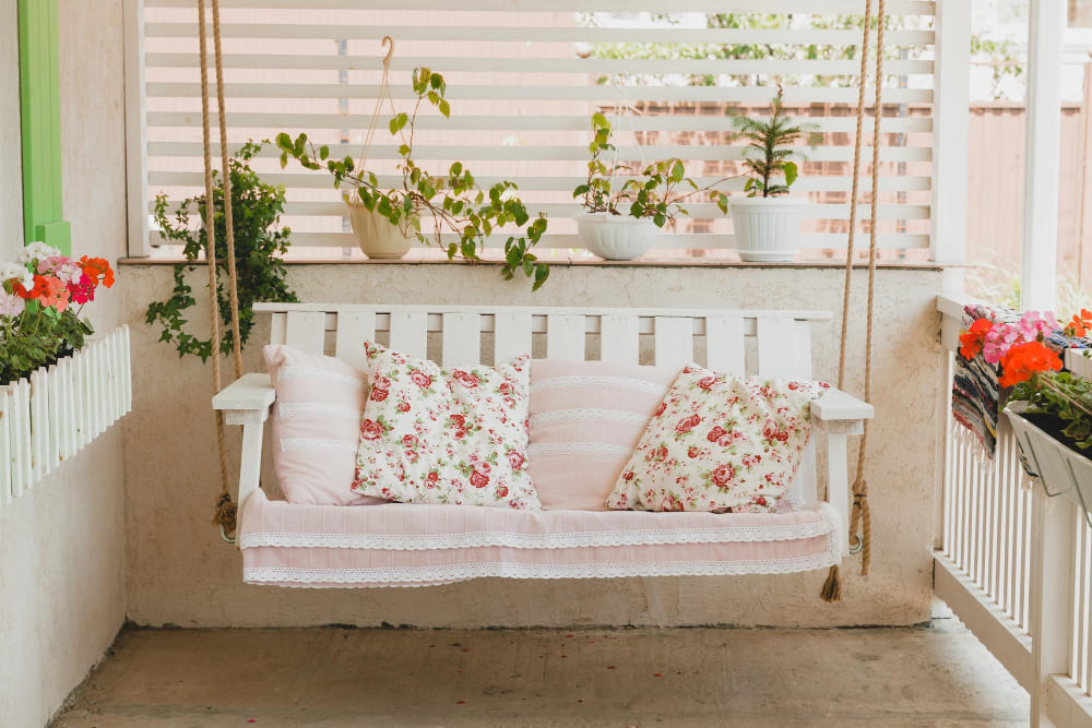 une décoration balcon étroit avec une balancelle blanche suspendue, et coussins style rustique