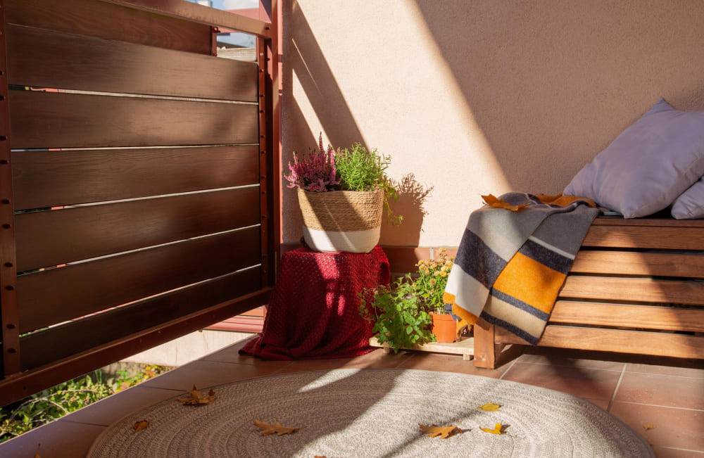 une décoration balcon étroit avec un pot de fleurs, un plaid et des coussins