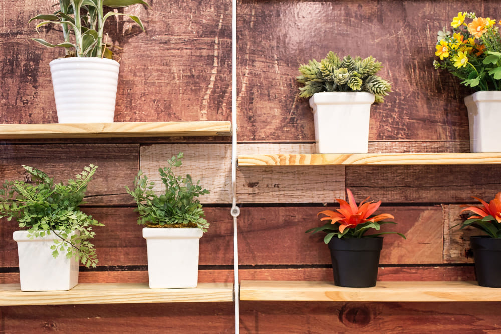 une étagère en bois contre le mur, avec des pots de fleurs blancs