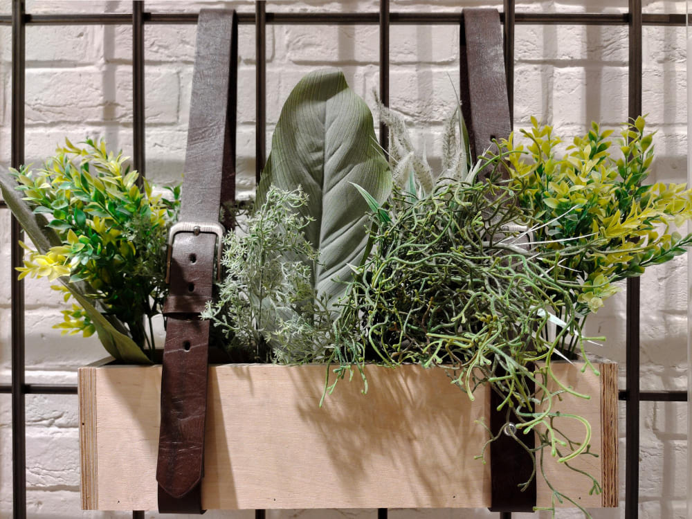 une jardinière de plantes diy suspendue sur la rambarde, avec des ceintures en cuir