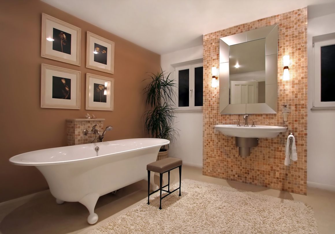 Salle de bains terracotta avec baignoire élégante, miroir chic, murs en mosaïque, lumière douce, plantes vertes
