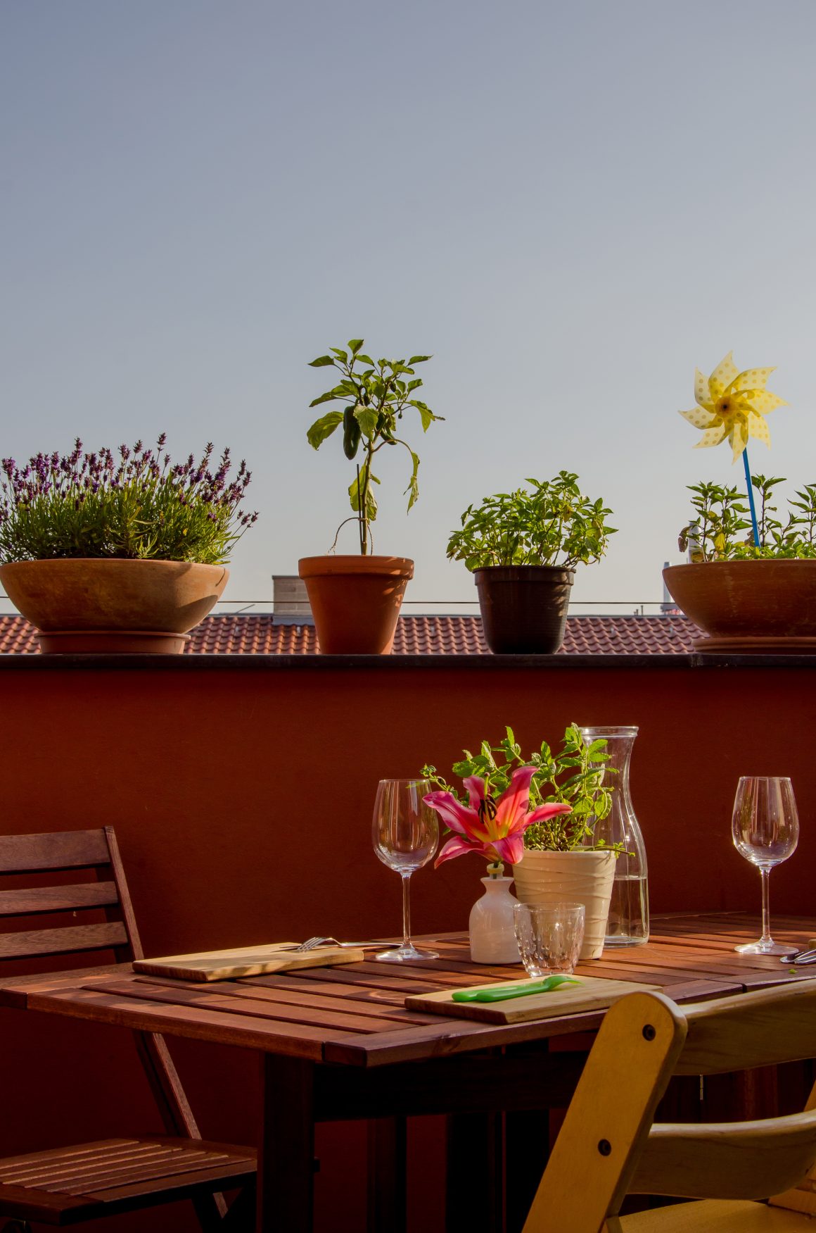 aménagement petit balcon avec une table en bois ornée d'une vase avec fleurs, avec des pots de plantes et d'autres éléments décoratifs.