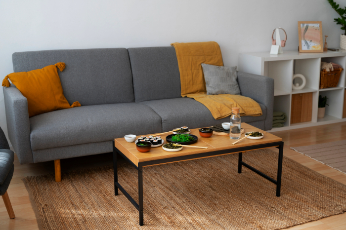 salon accueillant avec un canapé 2 places gris, des coussins, une table en bois et des accessoires.