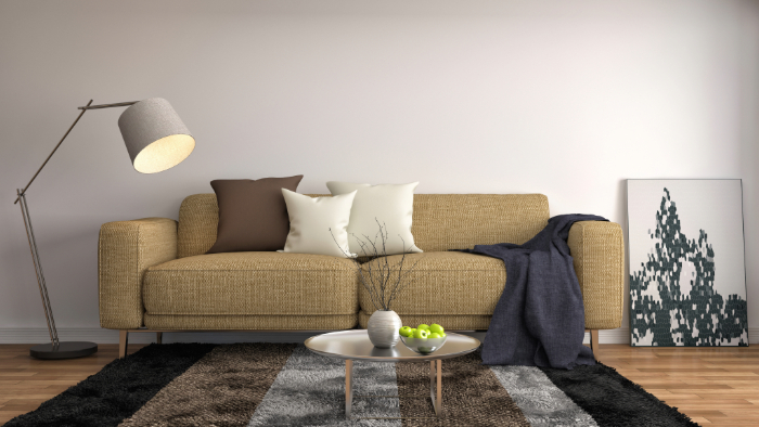salon moderne incluant un canapé beige, des coussins, une lampe, une table basse et une œuvre murale.