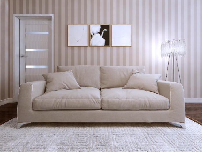 Un salon moderne avec un canapé beige, un tapis, des œuvres d'art et une lampe.