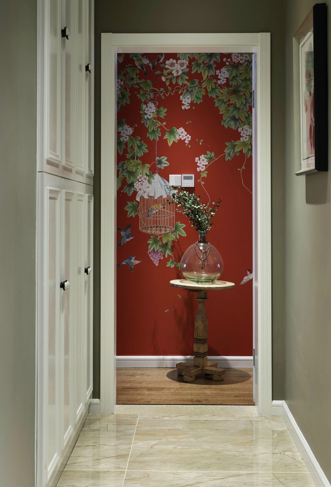 couloir élégant avec un mur rouge, des fleurs, une table en bois et une vase.