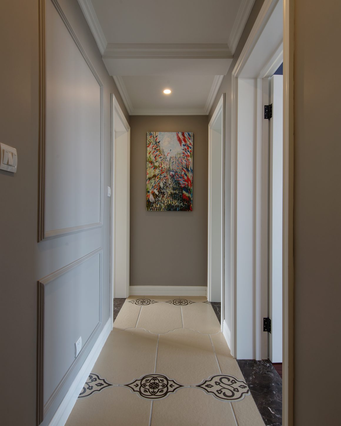 Un couloir moderne avec des murs gris, un tableau coloré et un carrelage décoratif.