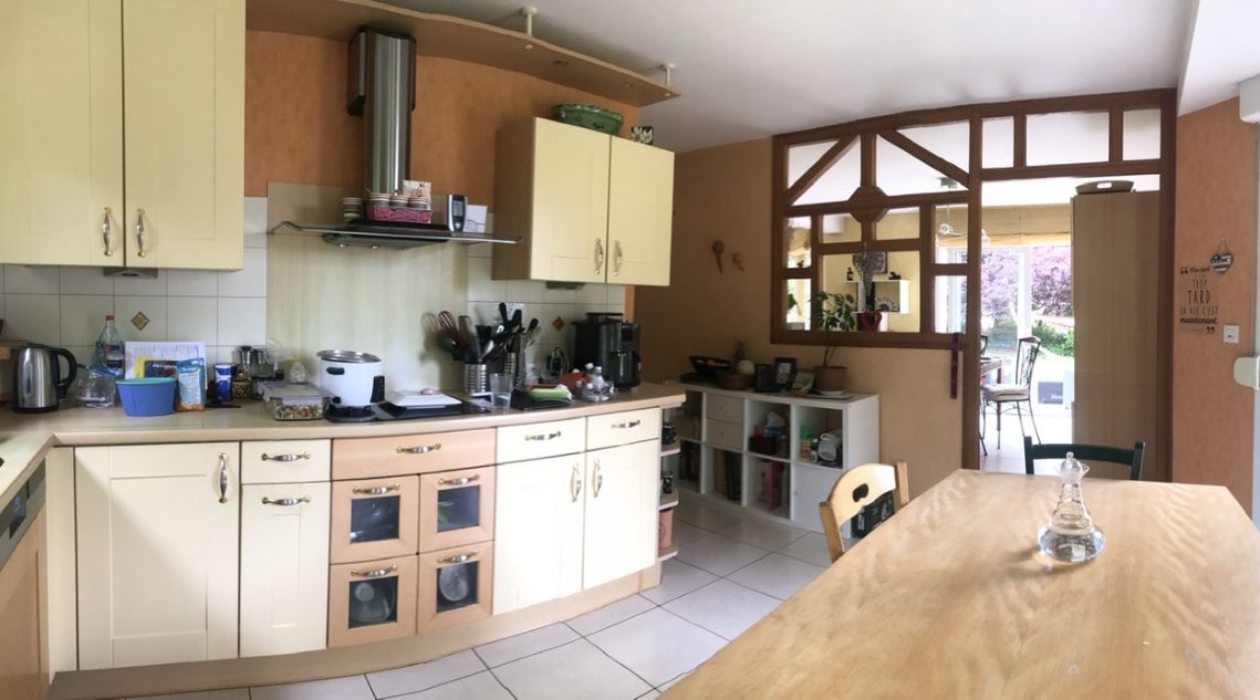 ancienne cuisine en L, avec des meubles d'aspect vieillot et une cloison faite avec du bois