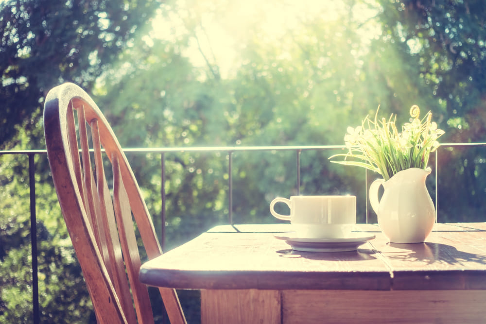 une table en bois sur un petit balcon, avec une tasse et un vase en porcelaine