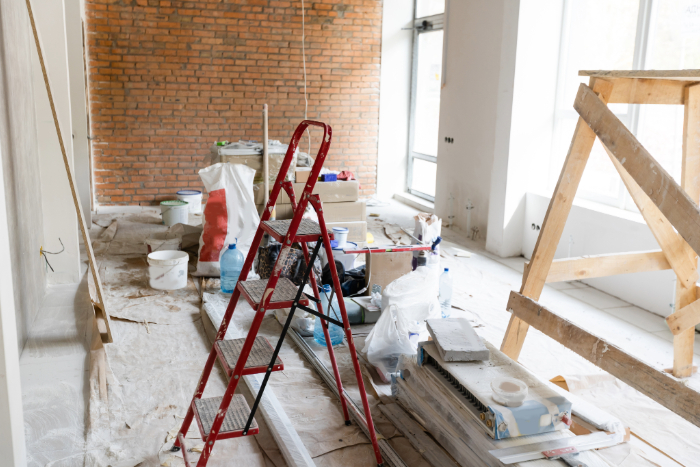 pièce d'une maison ancienne en rénovation avec échelle, outils, et matériaux de construction.