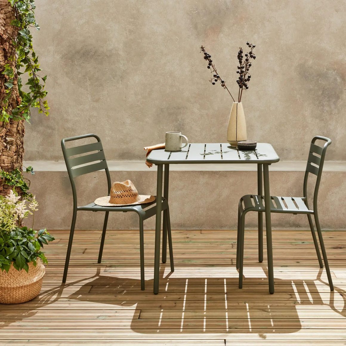 une petite table et deux chaises en métal sur le balcon, avec un plancher au sol