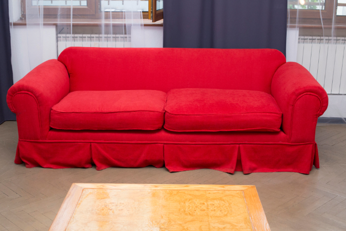 Un canapé rouge vif avec des coussins doux, placé dans un espace lumineux et accueillant.